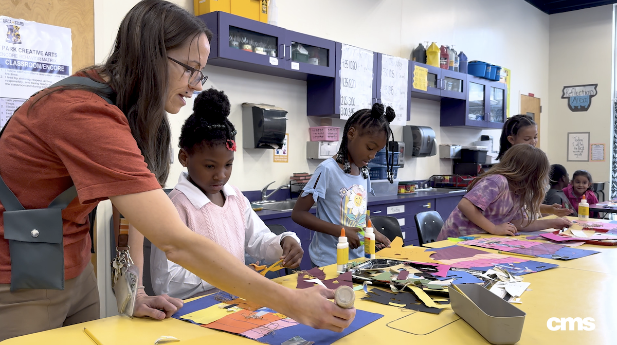  Art teacher assists children with their art project